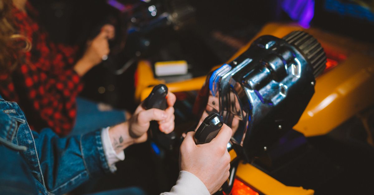 People enjoying a thrilling virtual reality driving simulation in a vibrant arcade setting.